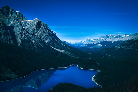 lake beside mountain under blue sky thumbnail