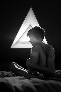 woman sitting on bed with lights turned off thumbnail