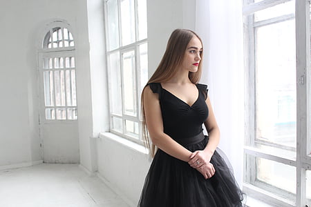 photo of woman wearing black plunging sleeveless dress standing near window thumbnail