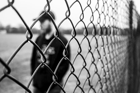 man standing beside gray stainless steel wire fence thumbnail