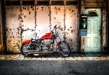 parked red motorcycle outside white metal walled building with green door thumbnail