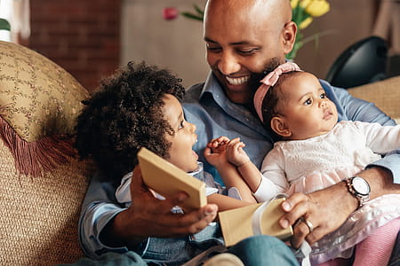 Young Boy Smiles At Father Holding Baby Sister Photo thumbnail