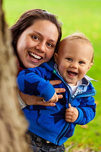 woman holding baby in blue zip-up hoodie focus photo thumbnail