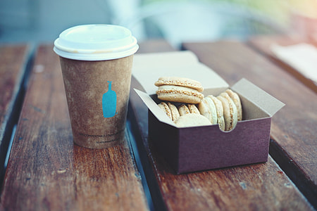 assorted pastry in box beside brown disposable plastic cup thumbnail