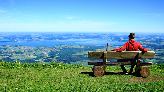 man in red pullover hoodie sitting on brown wooden bench over-viewing planes thumbnail