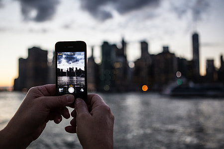 An iPhone mobile smartphone user captures the Manhattan skyline from DUMBO in Brooklyn, New York City thumbnail