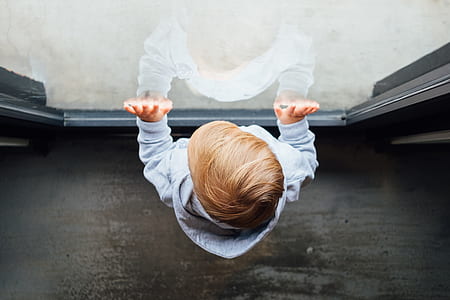 high angle photo of boy standing in front of glass window thumbnail