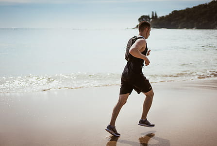 Man Wearing Black Tank Top and Running on Seashore thumbnail