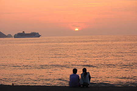two people sitting on seashore during sunset thumbnail