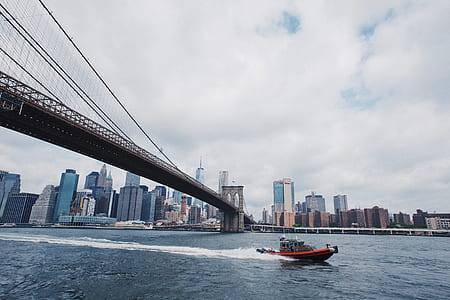 red power boat passes under bridge over body of water thumbnail