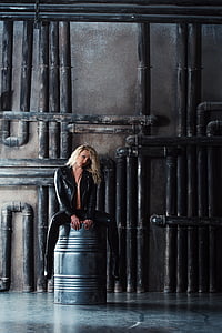 woman wearing black leather jacket seating on a silver drum thumbnail