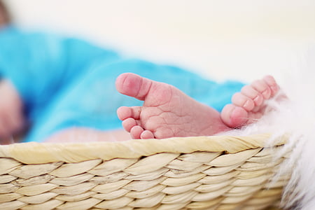baby's feet on beige wicker basket thumbnail