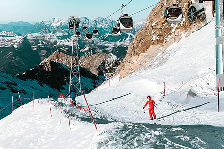 man standing on snowfield below the cable cart during day time thumbnail