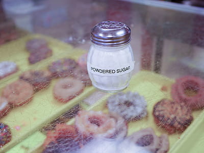 Powdered sugar in a glass shaker sitting in a donut shop. thumbnail