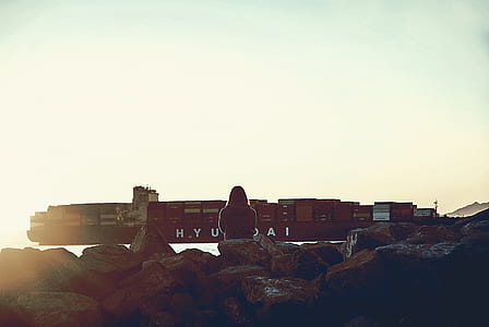 woman sitting on stone beside ship thumbnail