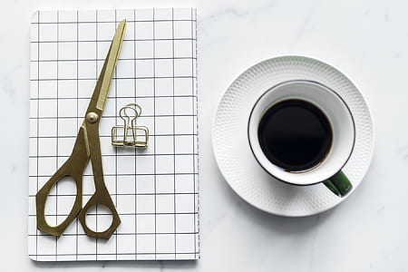 flat-lay photography of cup with coffee on saucer and scissors thumbnail