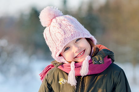 girl in green thermal jacket with pink pompom knit cap smiling thumbnail