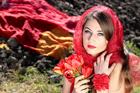 woman holding bouquet of red flowers wearing red headdress thumbnail