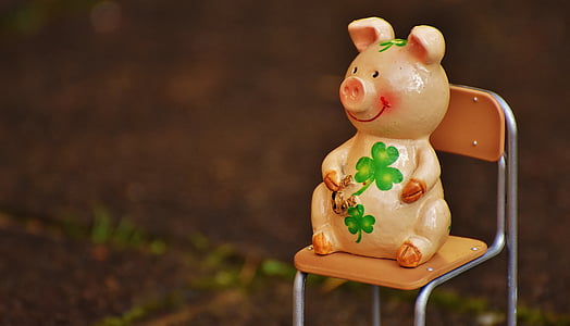 orange, green, and brown ceramic pig figurine on brown chair thumbnail
