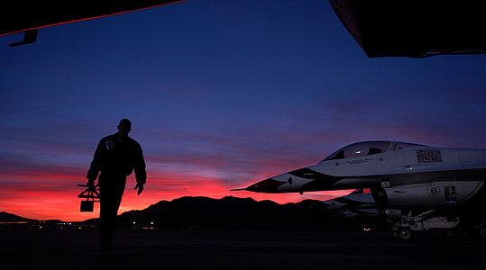man walking near white aircraft under pale evening sky thumbnail