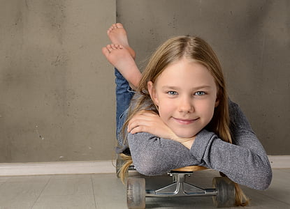 girl wearing gray sweater lying on skateboard thumbnail