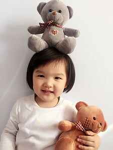 girl holding brown bear plush toy thumbnail