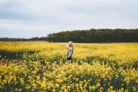 woman standing round of yellow flowers during daytime thumbnail
