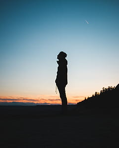 silhouette of man standing near trees during sunset thumbnail