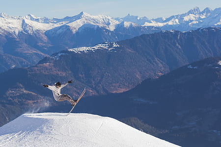 skier hurdling over a snow mound during daytime thumbnail