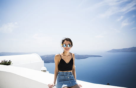 woman sitting on white paint concrete fence during daytime thumbnail