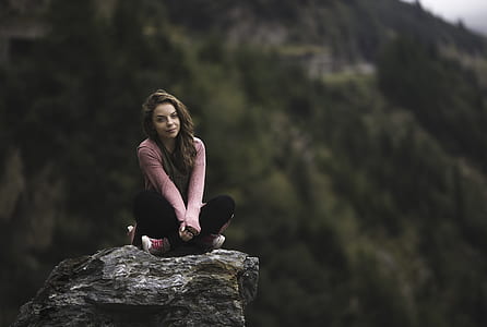 shallow focus photography of woman sitting on rock during daytime thumbnail