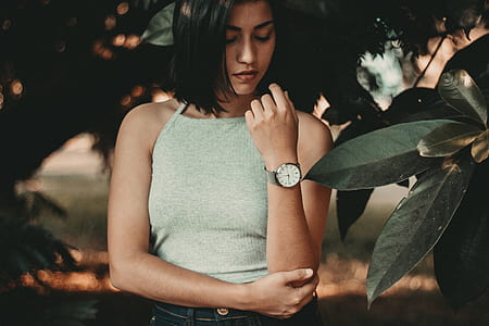 standing woman holding her left elbow near leaves thumbnail