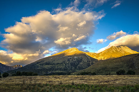 white nimbus cloed with beige and brown mountains thumbnail