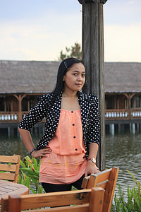 woman standing beside chair and table near body of water thumbnail