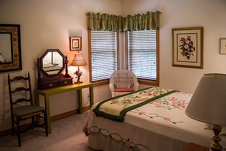 white rattan armchair on corner of a bedroom near beda thumbnail