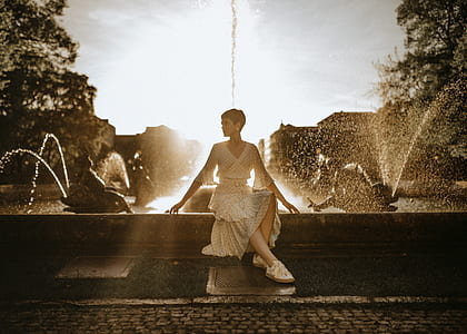 woman wearing v-neck dress sitting beside fountain thumbnail