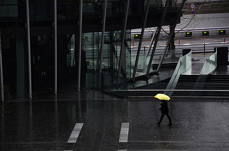 person walking on the street holding his yellow umbrella while raining thumbnail