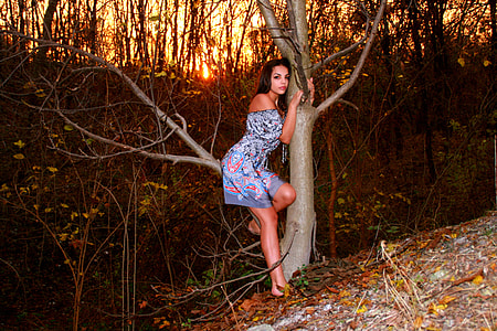 woman in gray and pink off-shoulder mini dress sitting on brown tree branch under clear sky during daytime thumbnail