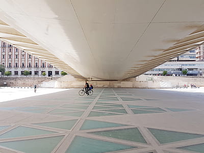 man riding on bicycle under bridge thumbnail