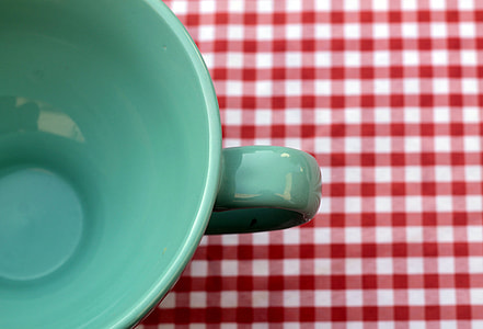 green ceramic cup on red and white textile thumbnail