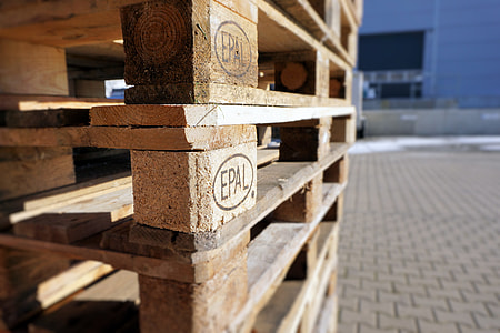 closeup photo of piled brown wooden pallets on gray concrete floor thumbnail
