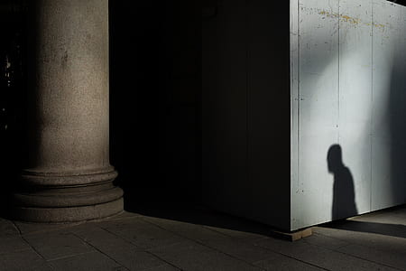 person standing near wall casting shadow thumbnail