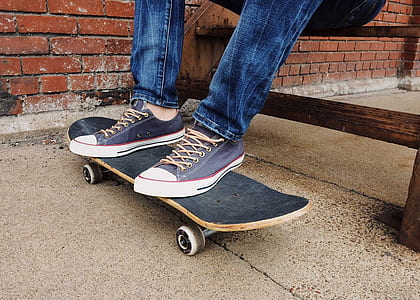 man sitting while putting his feet on top of gray skateboard thumbnail