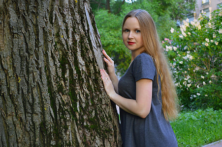 woman wearing gray shirt leaning on tree thumbnail