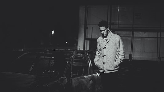 man standing beside a burned vehicle in grayscale photography thumbnail