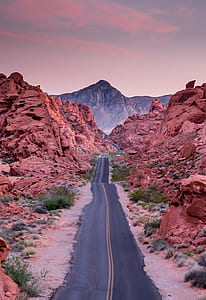 gray asphalt road between rocks thumbnail