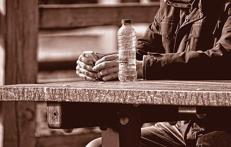 grayscale photography of man sitting on picnic table thumbnail