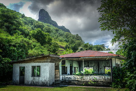 gray concrete house beside mountain under white cloudy sky thumbnail