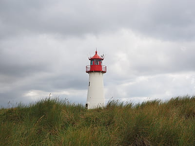 white and red lighthouse under cloudy sky thumbnail