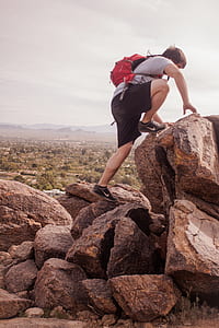 man carrying bag climbing up boulder thumbnail